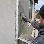 25x25mm white PVC render corner bead being installed on an external rendered building corner by a plasterer