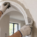 Close-up of flexible 25x25mm PVC arch render corner bead being embedded into fresh plaster around an arch