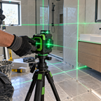 Close-up of 360 degree 5-line green laser level on tripod aligning bathroom tiles and fixtures