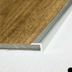 Close-up of a wooden floor with a metal threshold on a white background