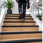 A32 65x42mm anodised aluminium non-slip ribbed stair nosing installed on a modern staircase with a person using the stairs