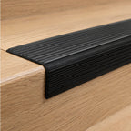 Close-up of A38 46 x 30mm anodised aluminium non slip rubber stair nosing installed on a wood-effect stair edge