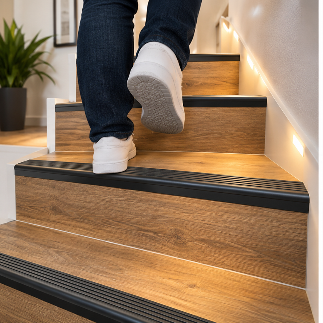 A41 35 x 35mm anodised aluminium non slip ribbed stair nosing installed on wood-look residential stairs with a person using the staircase